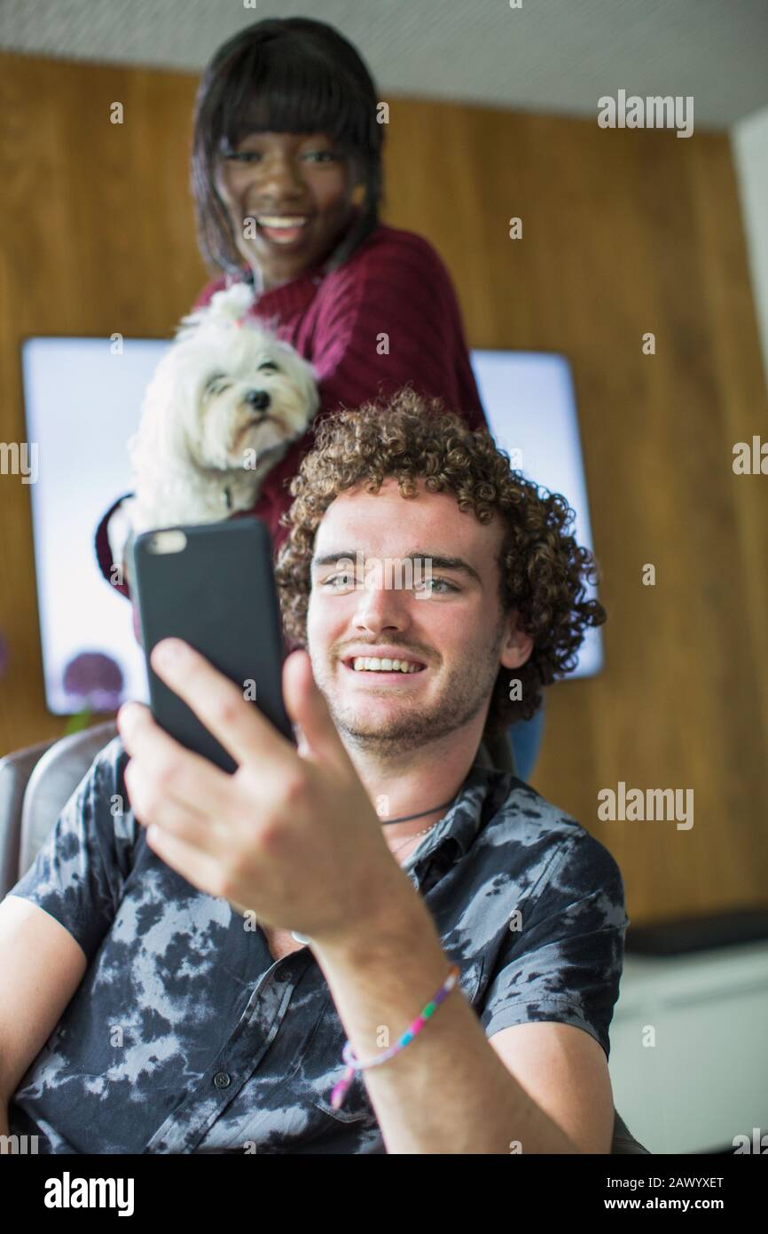 Happy young couple with dog video chatting with smart phone Stock Photo