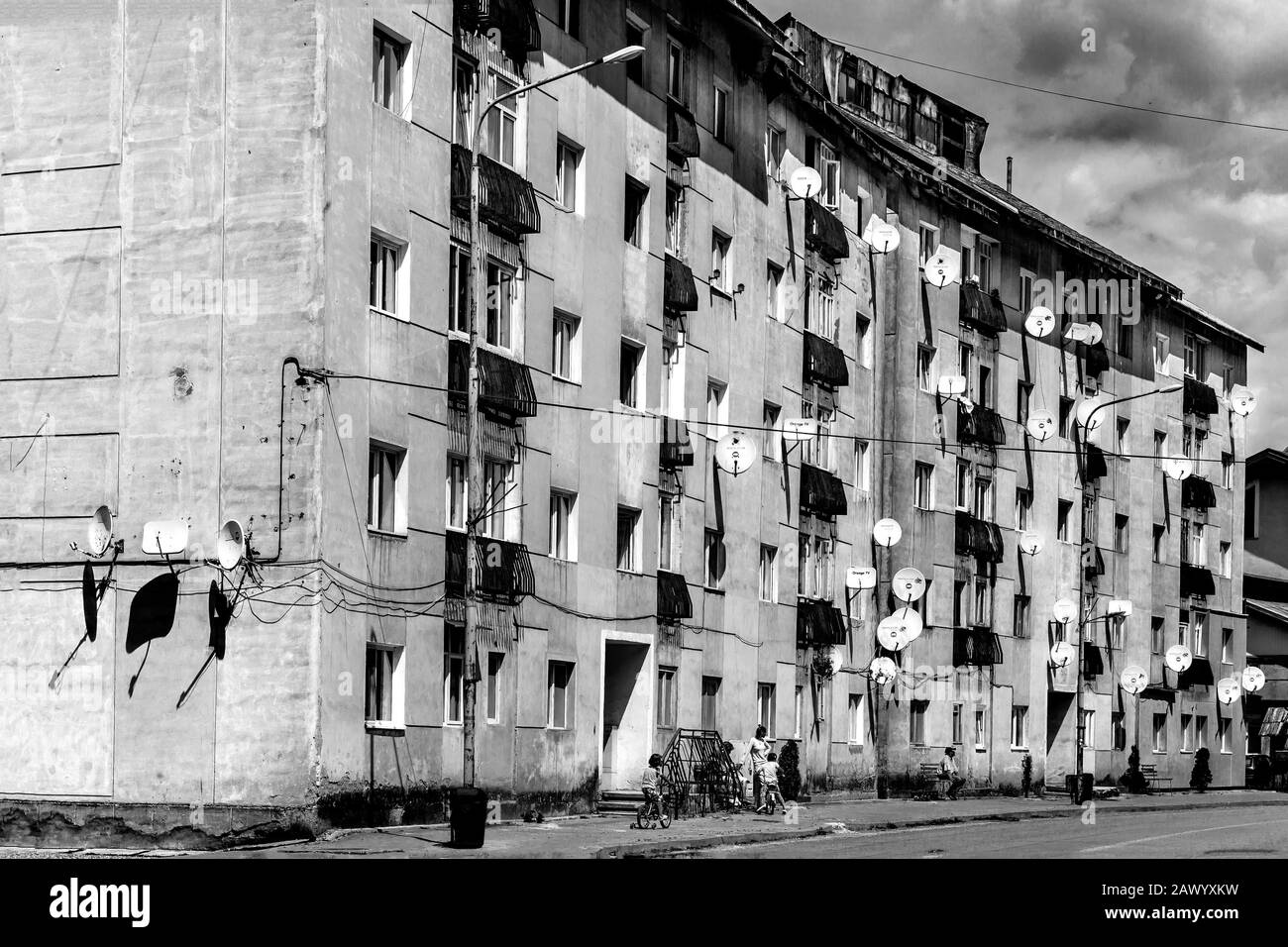 Greyscale of an apartment building under a cloudy sky and sunlight Stock Photo
