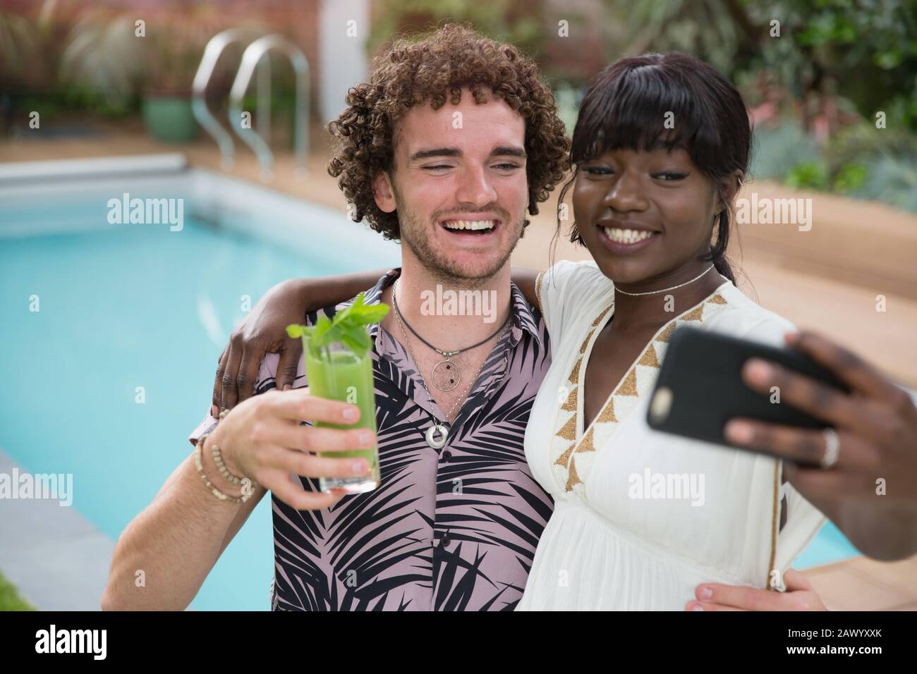 Happy young couple taking selfie with camera phone at poolside Stock Photo