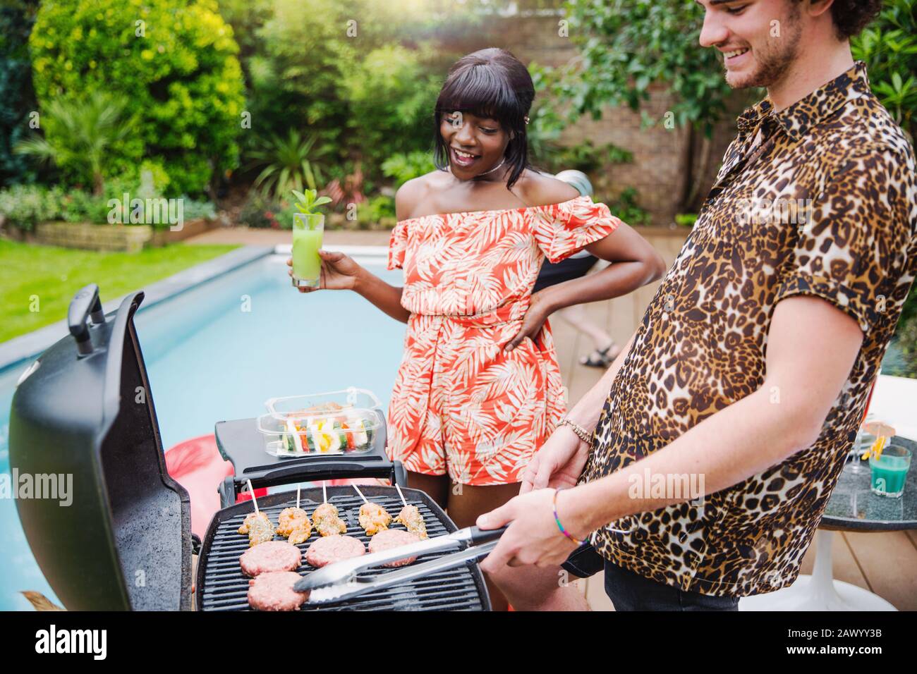Young multiethnic couple barbecuing at poolside Stock Photo