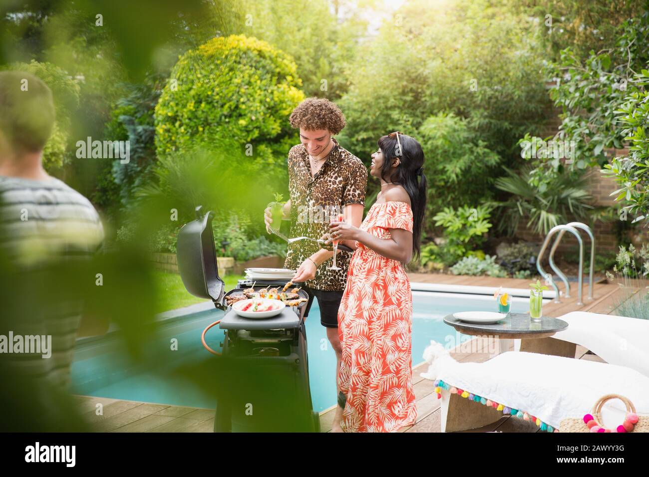 Young multiethnic couple barbecuing at summer poolside Stock Photo