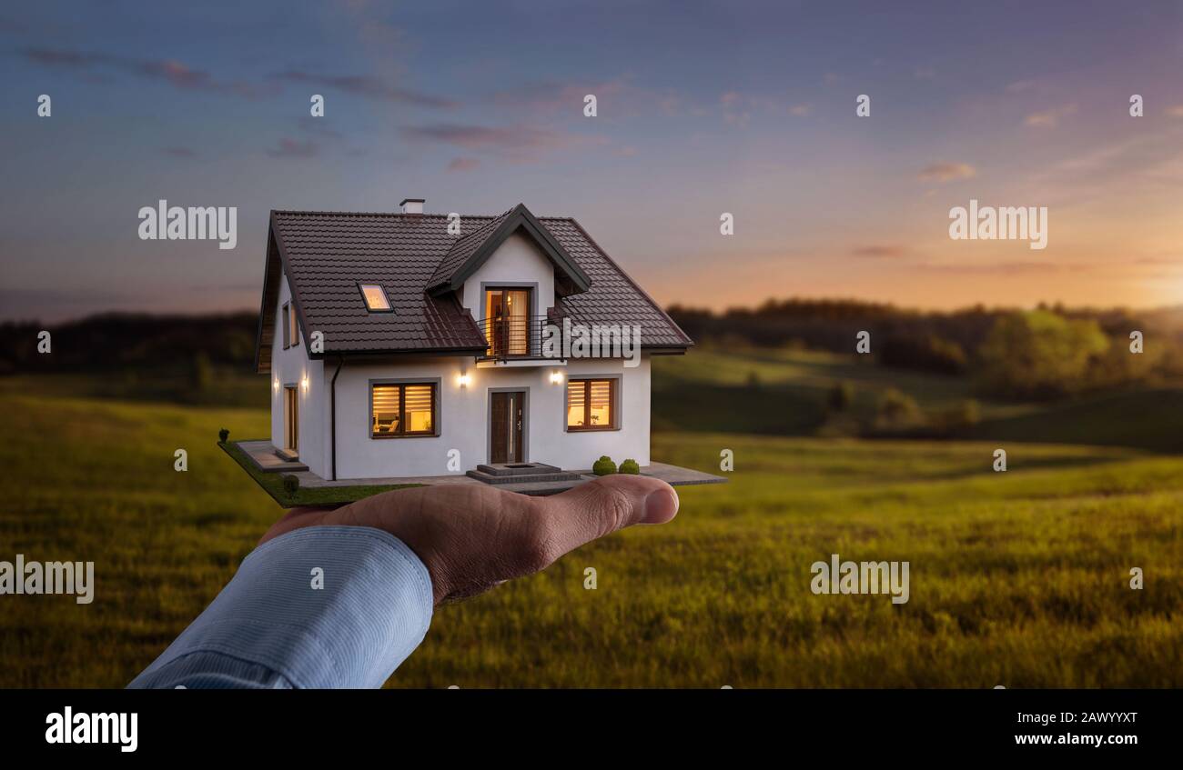 Concept of buying or building new home. Male hand showing, offering a new dream house at the empty field with copy space Stock Photo