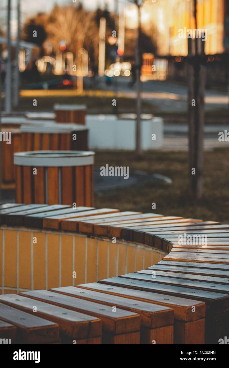 Vertical shot of a circular wooden bench surrounded by trash cans in a park Stock Photo