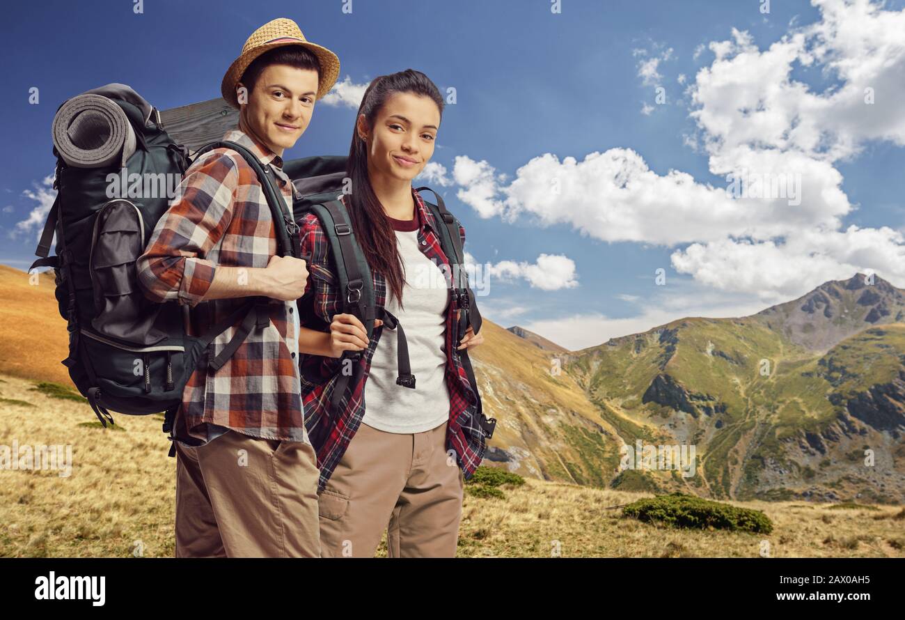 Young male and female hikers with backpacks posing on a mountain Stock Photo