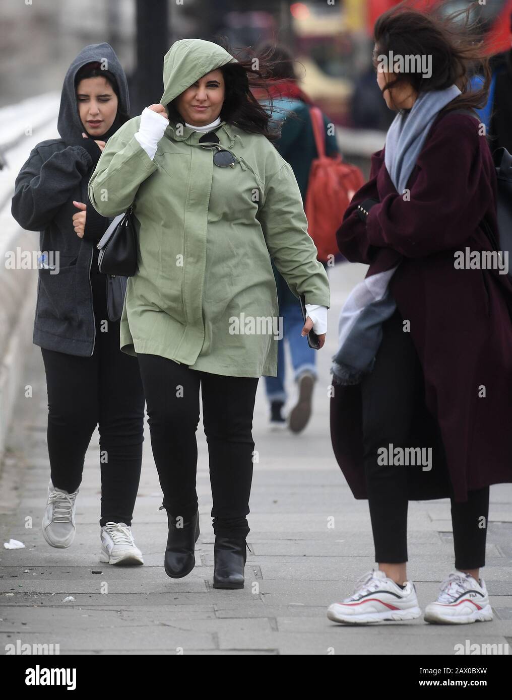 People walk through strong winds across Waterloo Bridge in London, the Met Office have said that 'a spell of very strong winds,' with gusts of 60-70mph, is expected across southern England on Monday, bringing likely delays to road, rail, air and ferry transport. Stock Photo