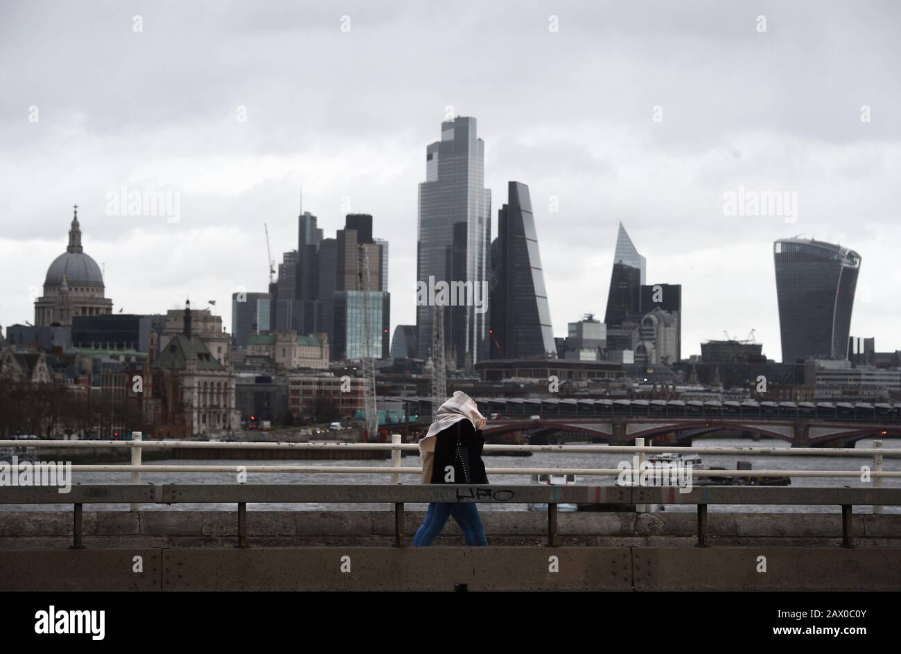 People walk through strong winds across Waterloo Bridge in London, the Met Office have said that 'a spell of very strong winds,' with gusts of 60-70mph, is expected across southern England on Monday, bringing likely delays to road, rail, air and ferry transport. Stock Photo