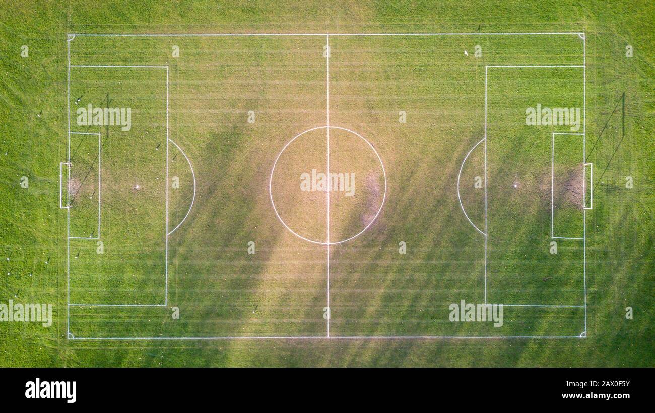 Football pitch. Aerial drone view looking down vertically onto an empty soccer pitch with shadows cast by the low sun. Stock Photo