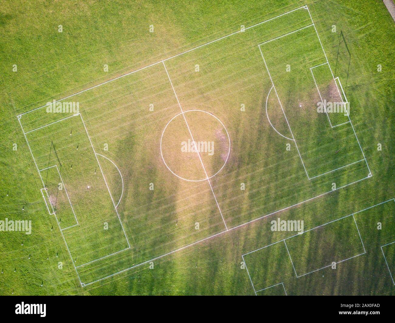Football pitch. Aerial drone view looking down vertically onto an empty soccer pitch with shadows cast by the low sun. Stock Photo