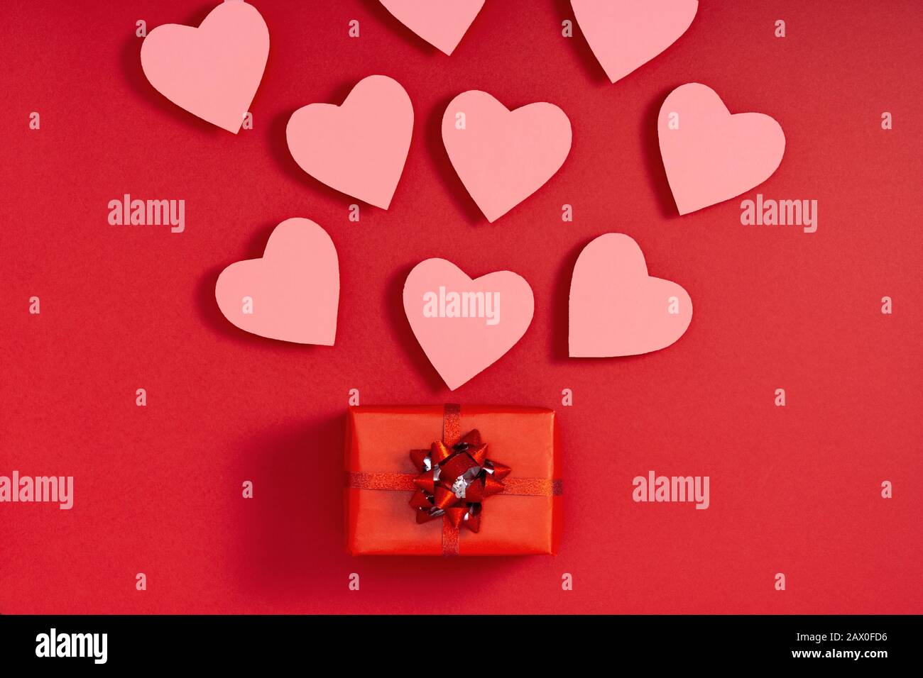 Gift box and valentine hearts on red surface. Present, surprise, congratulation. Top view, flat lay, from above Stock Photo