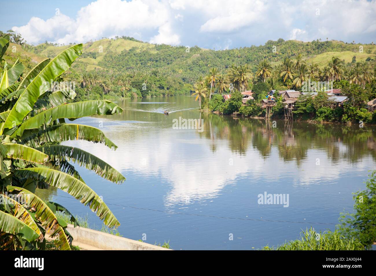River and green hills. Beautiful natural scenery of river in southeast Asia. Countryside on a large tropical island. Small village on the green hills by the river. The nature of the Philippines. Stock Photo