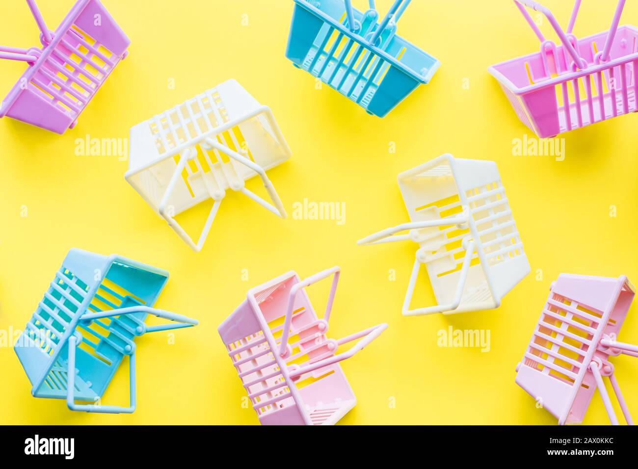 Pattern of colourful plastic shopping baskets on yellow background. Stock Photo