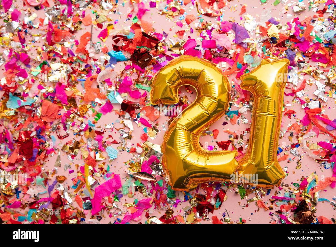 Number 21 gold birthday celebration balloon on a confetti glitter background Stock Photo