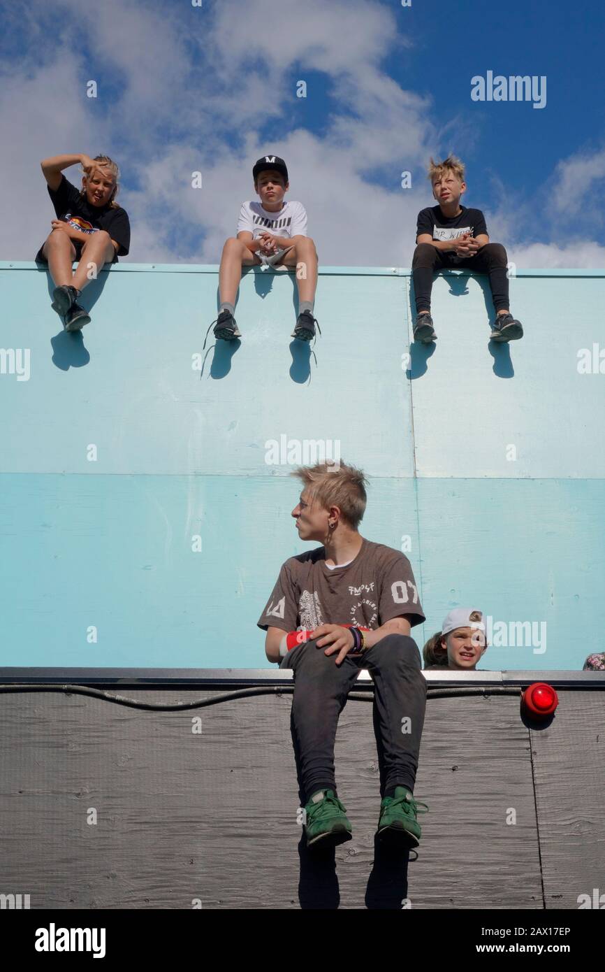 Parkour kids sit and relax on a edge of a building's terrace. Stock Photo