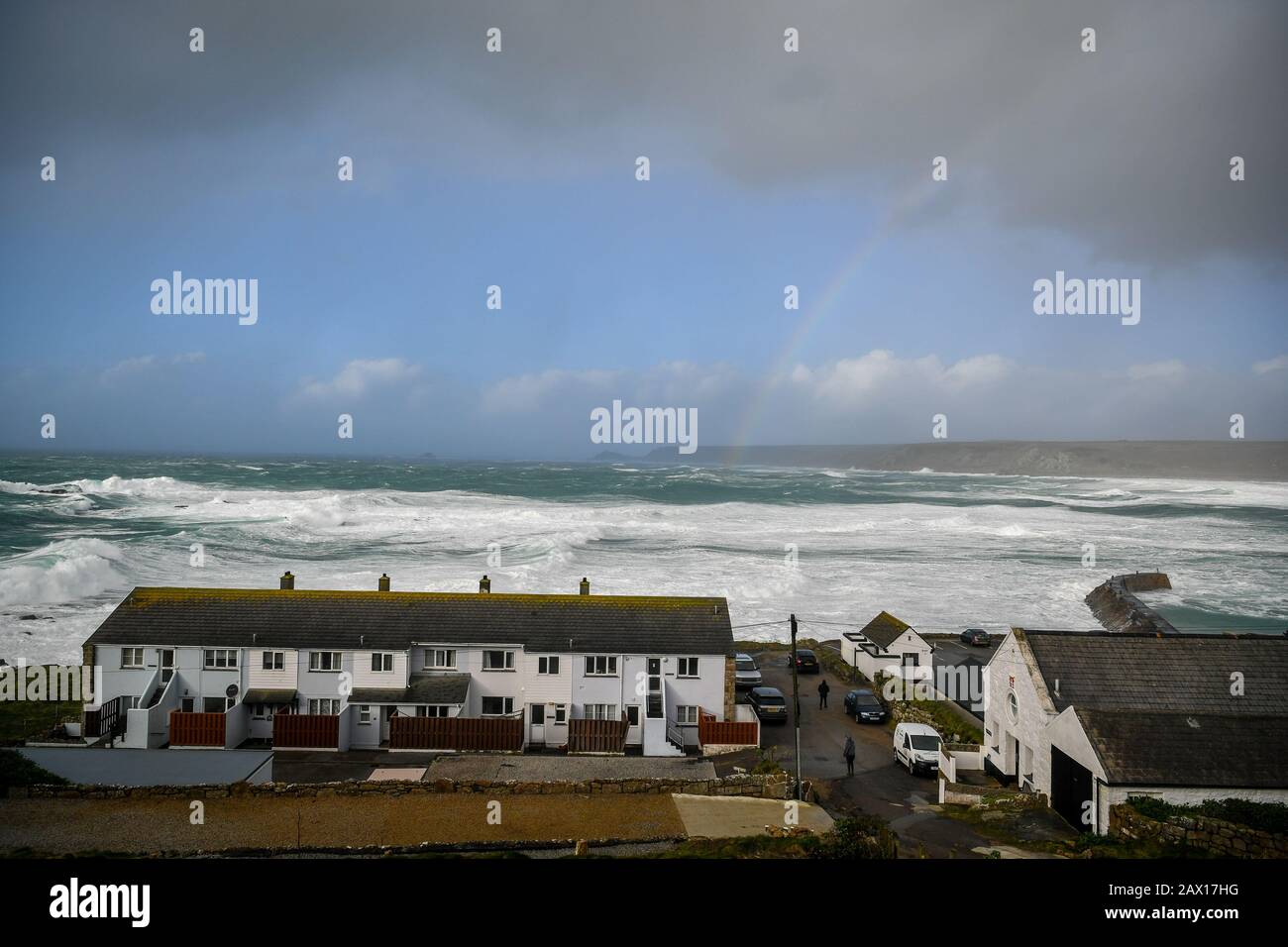 Rough seas beyond cottages in Sennen Cove, near Land's End, Cornwall, where a yellow wind warning is still in force as storm Ciara remains over some parts of the UK. Stock Photo
