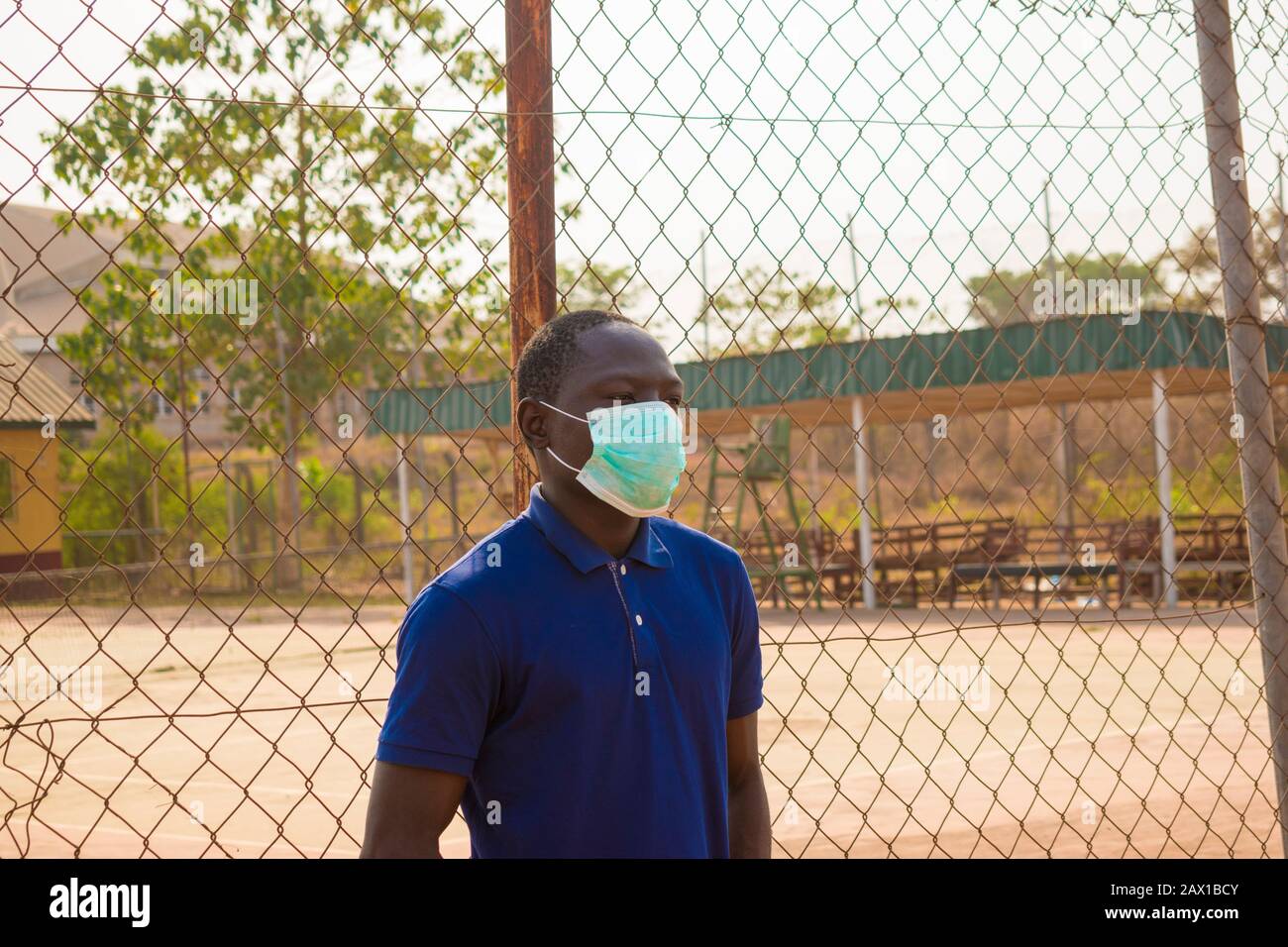 young black man standing alone outside wearing a medical face mask ...