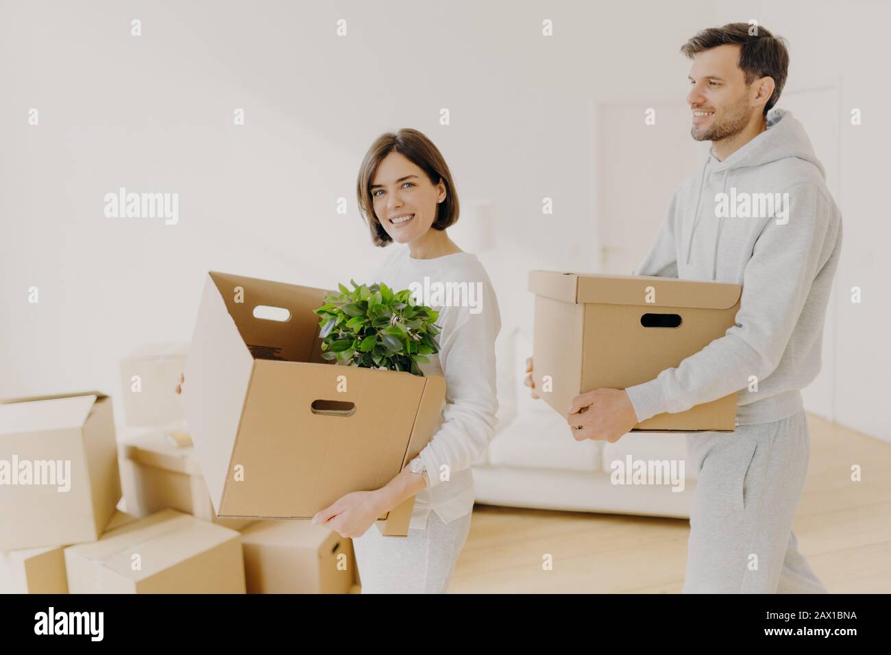 Photo of family couple carry big boxes with households items and personal belongings, move into new home, enter new bought or rented house. Happy home Stock Photo