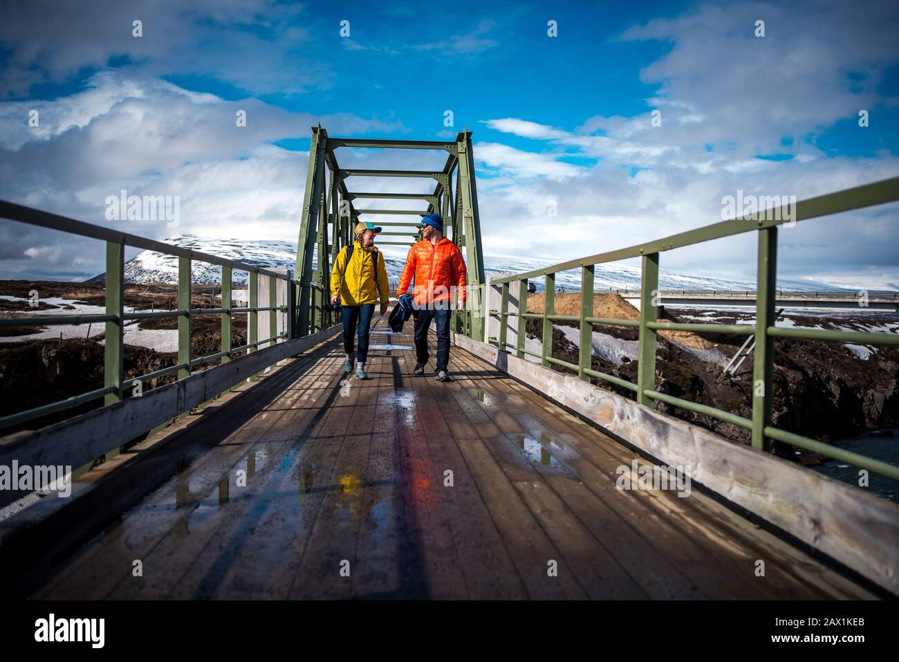 Man and woman in jackets walking across bridge in Iceland Stock Photo