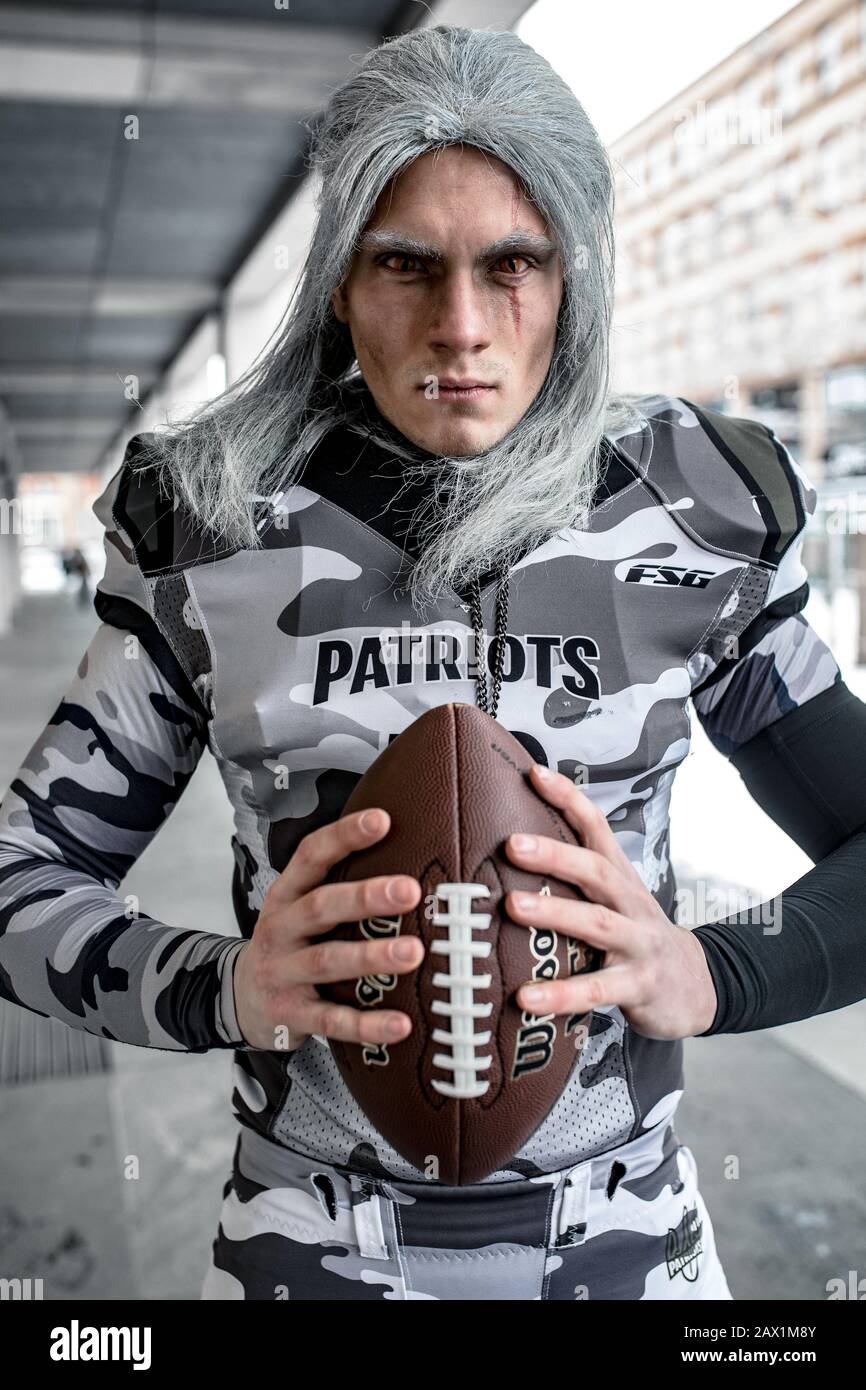 Man dressed as football team player in American football with ball in