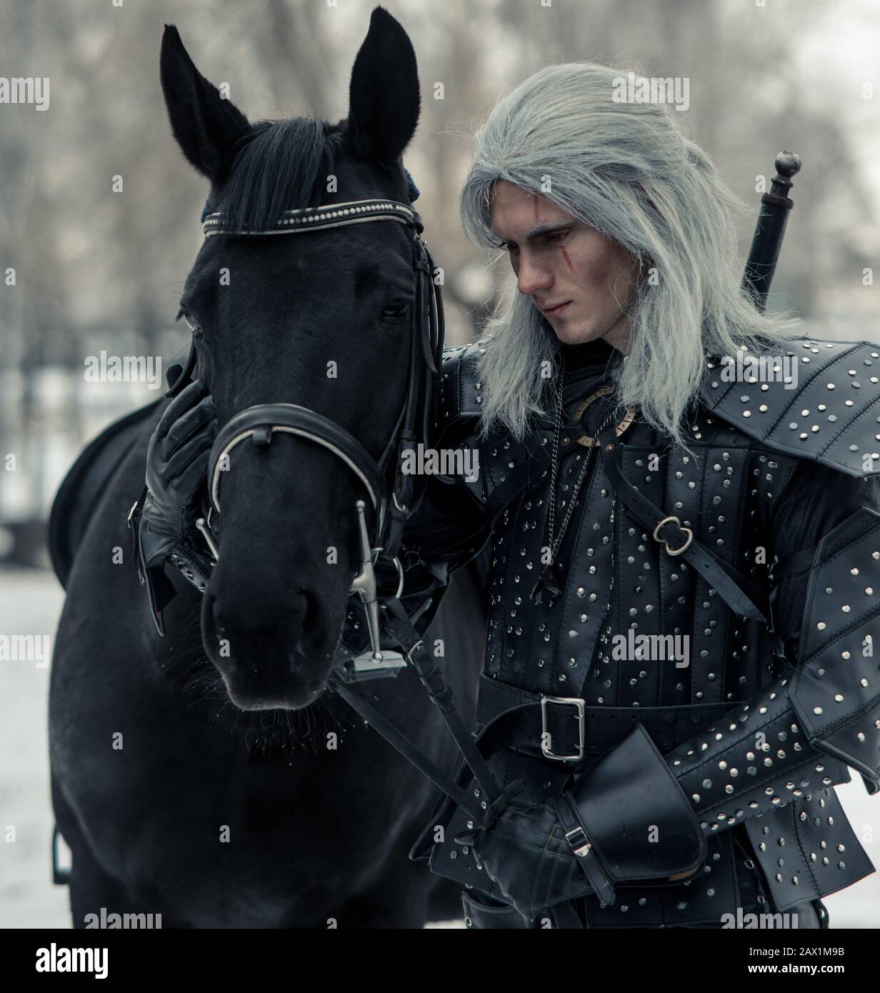 Portrait of man in image of ancient warrior witcher next to a horse in forest. Stock Photo