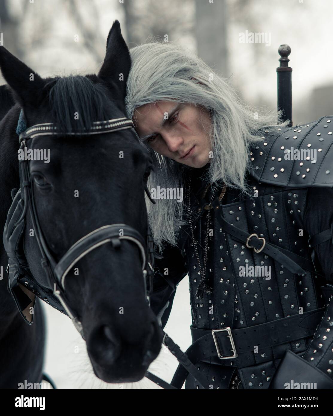 Portrait of man in image of ancient warrior witcher next to a horse in forest. Stock Photo