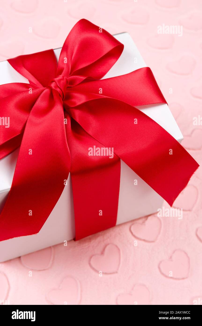 White Valentine's Day gift box with red bow sitting on a background of ...