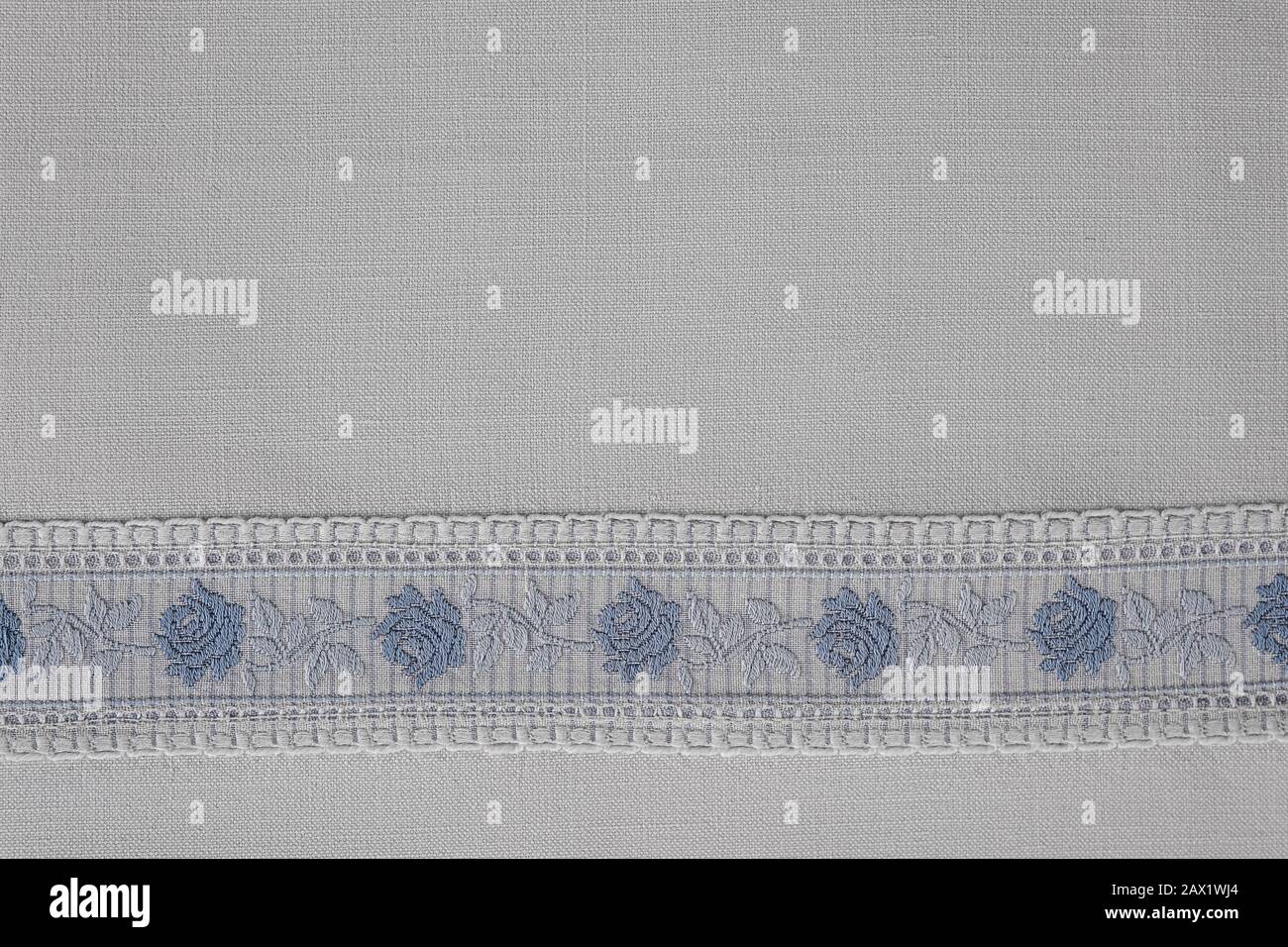 Embroidered border with roses in blue white on a white cotton table cloth Stock Photo