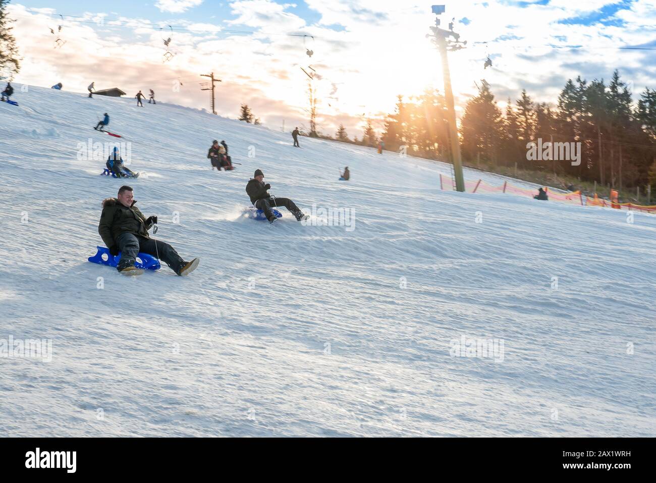 Winterberg, North Rhine Westphalia / Germany - December 30th 2019: There is a toboggan lift on the Sahnehang. Winter fun for families in the sunshine. Stock Photo
