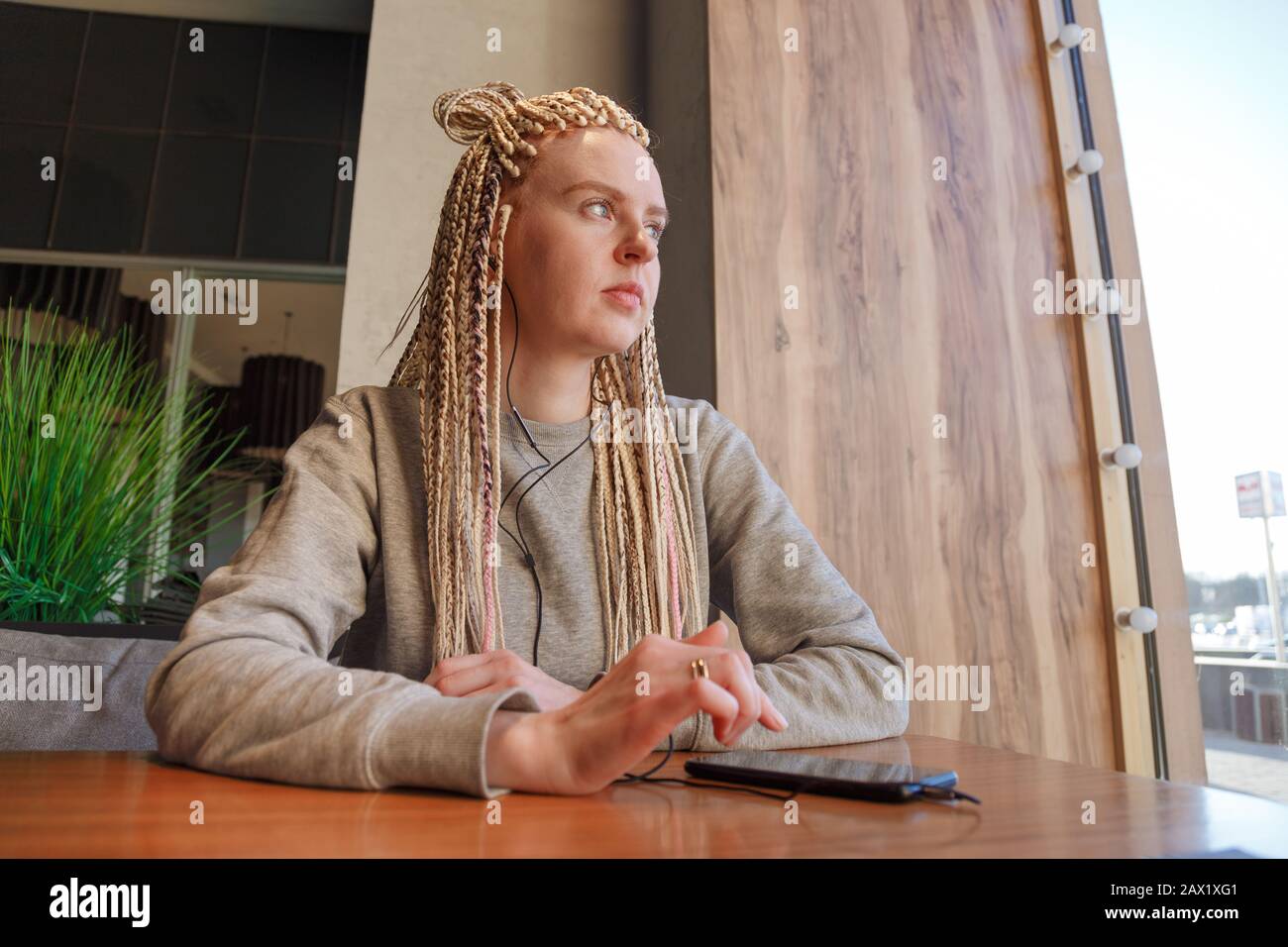 Worried young hipster woman in cafe. Lateness or punctuality concept. Stock Photo