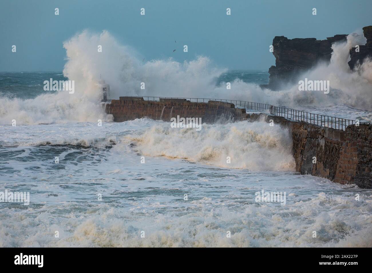 Storm Ciara batters the Cornish coast with giant waves as tall as the surrounding cliffs crashing against the breakwater Stock Photo