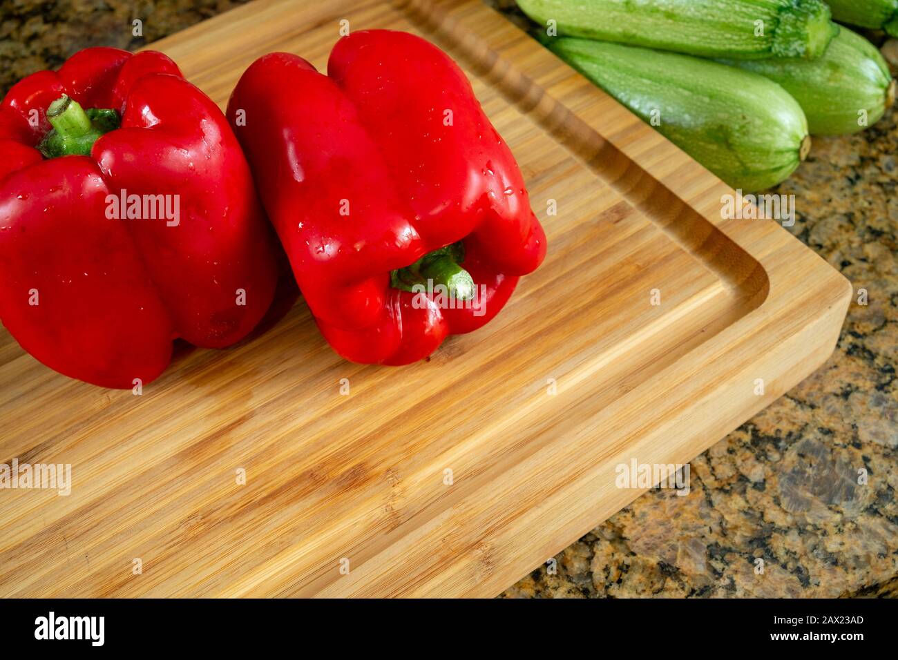 Red peppers and zucchini in a wooden cutting board, realistic approach to imperfect food ingredients. Stock Photo