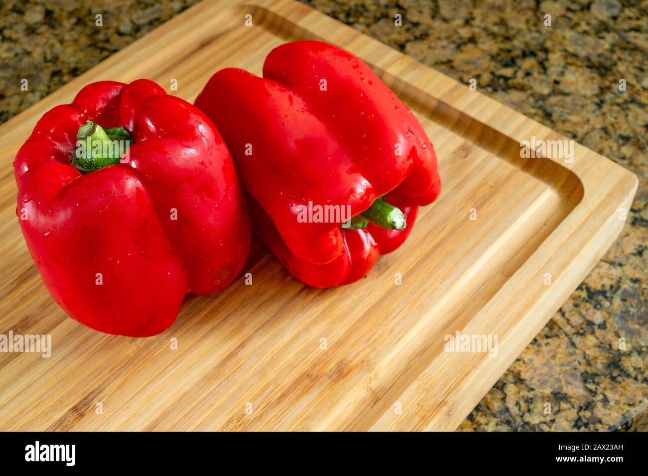 Red peppers in a wooden cutting board, realistic approach to imperfect food ingredients. Stock Photo