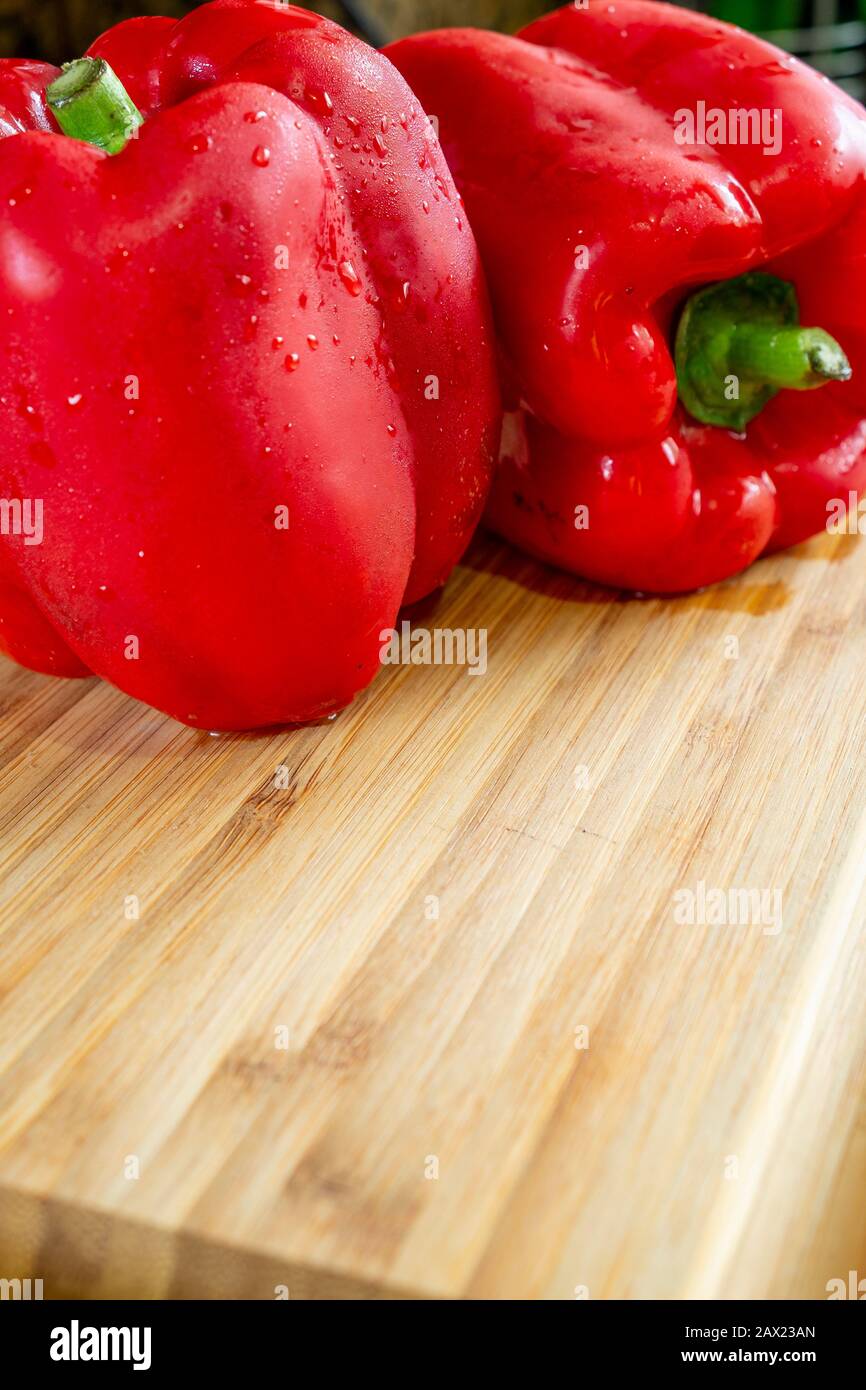 Red peppers in a wooden cutting board, realistic approach to imperfect food ingredients. Stock Photo