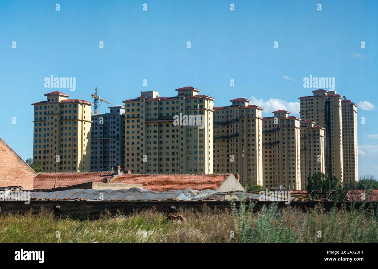 High rise apartment tower block buildings towering above traditional low buildings seen from Trans-Mongolian Express train, Jining, China, Asia Stock Photo