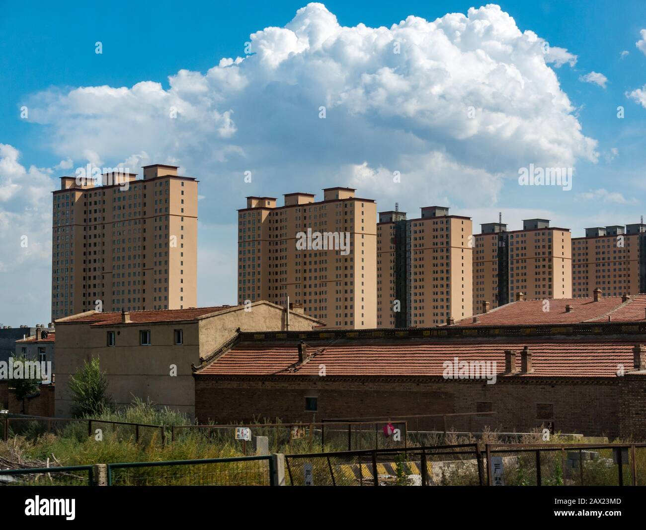 High rise apartment tower block buildings above traditional old buildings seen from Trans-Mongolian Express train, Jining, China, Asia Stock Photo