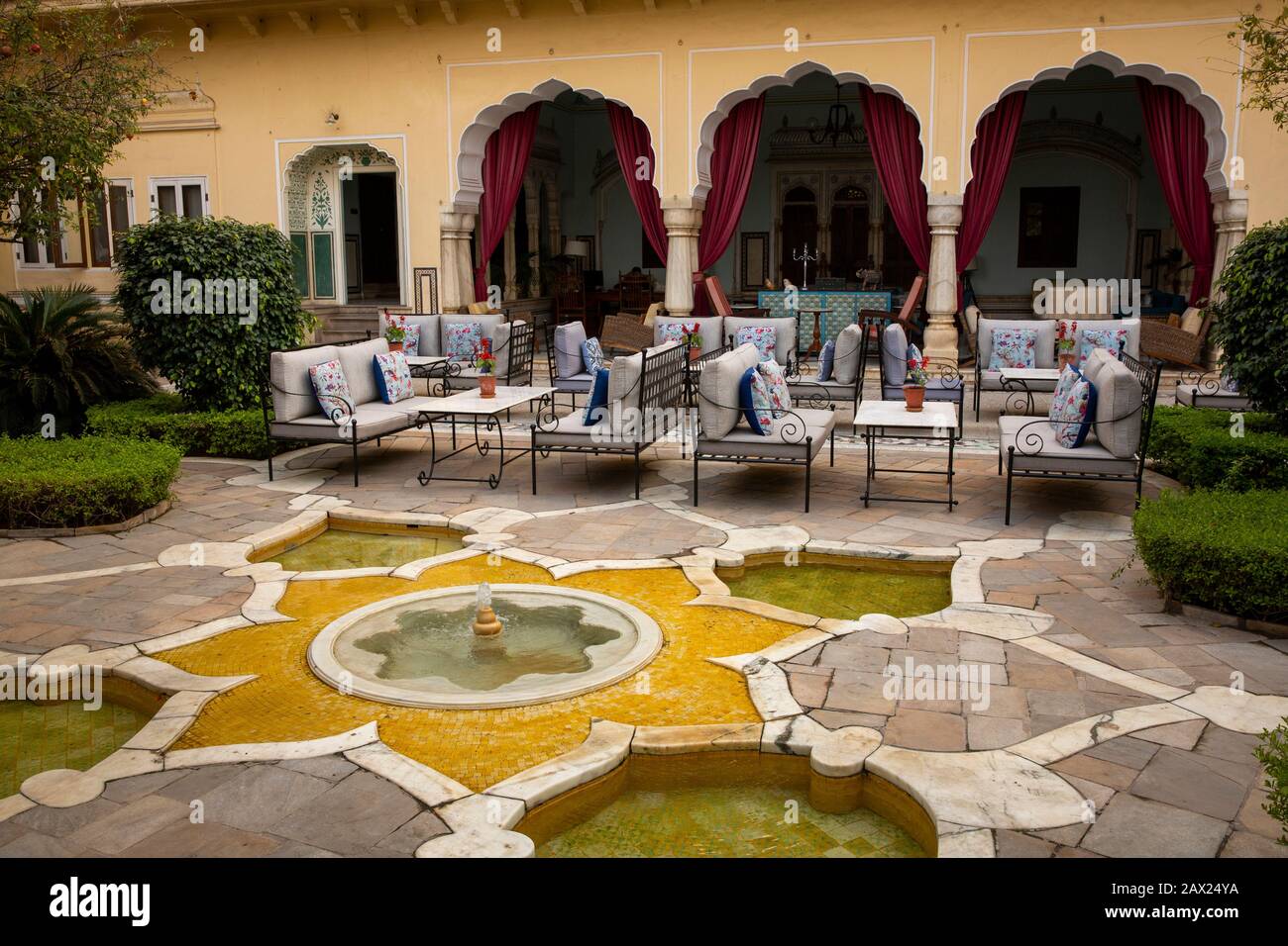 India, Rajasthan, Jaipur, Gangapole, Samode Haveli Hotel, in townhouse of Samode Royal Family, sitting area in courtyard amongst water feature Stock Photo