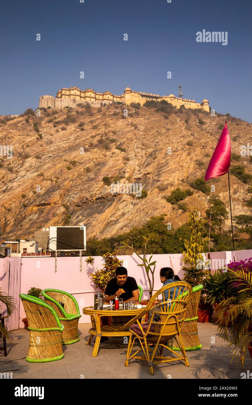 India, Rajasthan, Jaipur, Nahargarh Road, Nahargarh Fort towering above Nahargarh Palace hotel customer  in rooftop restaurant Stock Photo