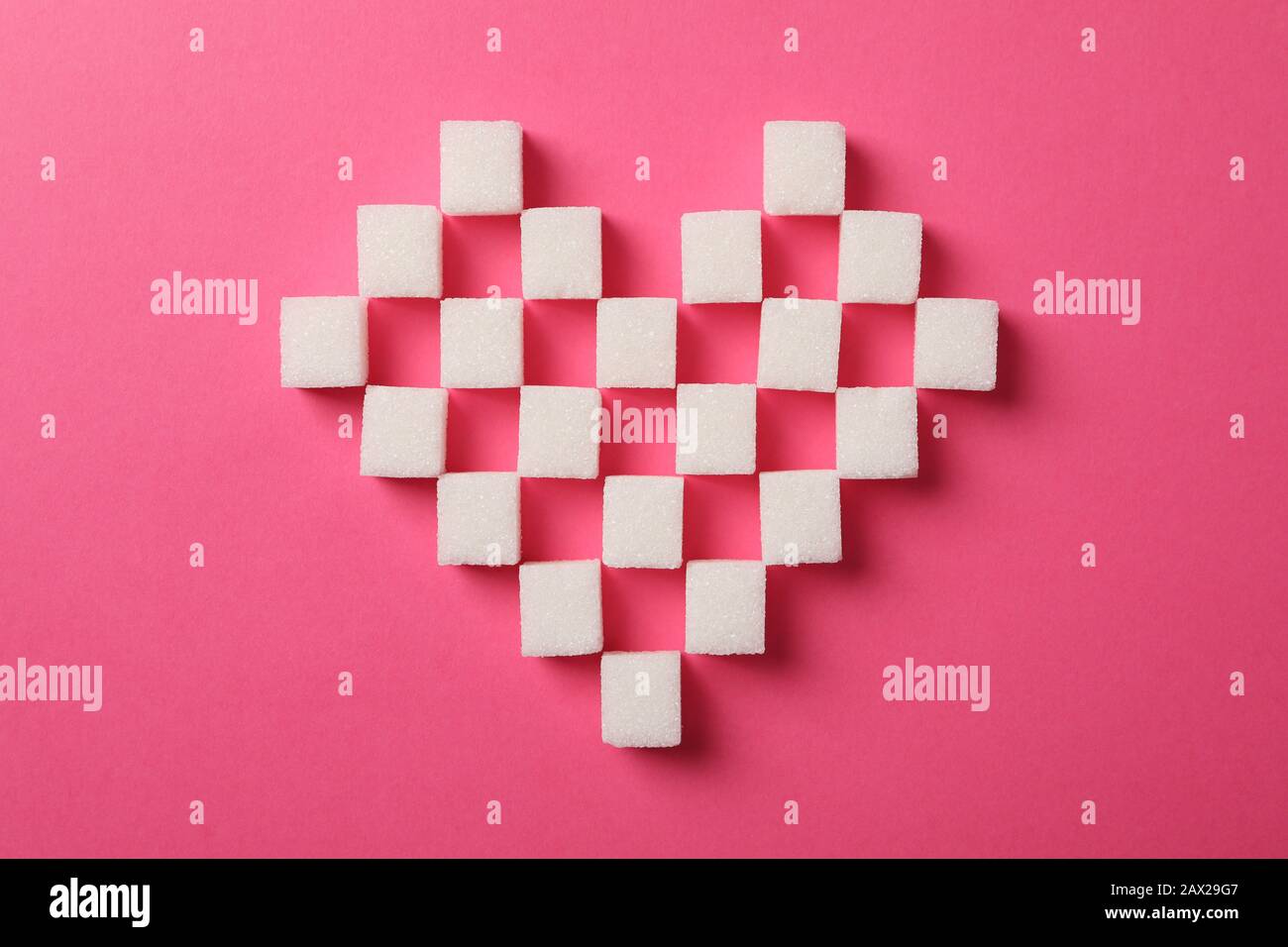 Heart made of sugar cubes on pink background, top view Stock Photo