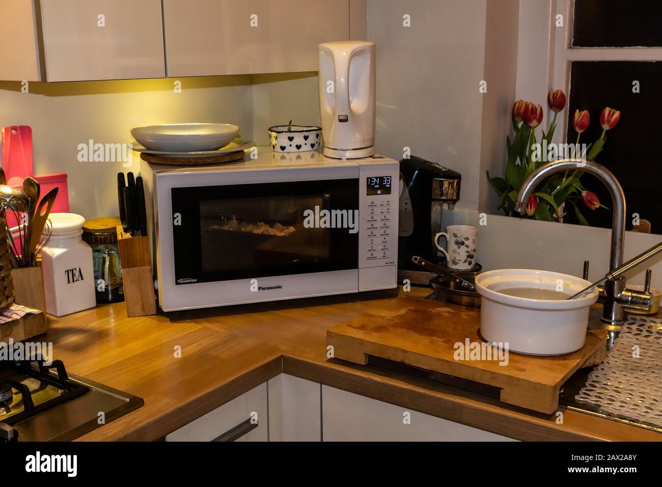 Cooking in a small kitchen- showing both the economical use of space to cook homemade food, alongside its hazards. Stock Photo