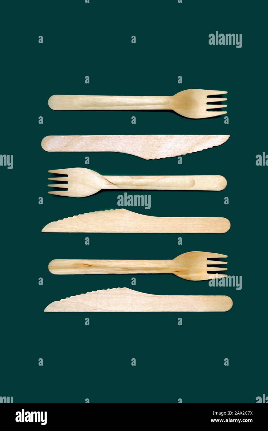 Set of disposable wooden knives and forks on a dark green emerald