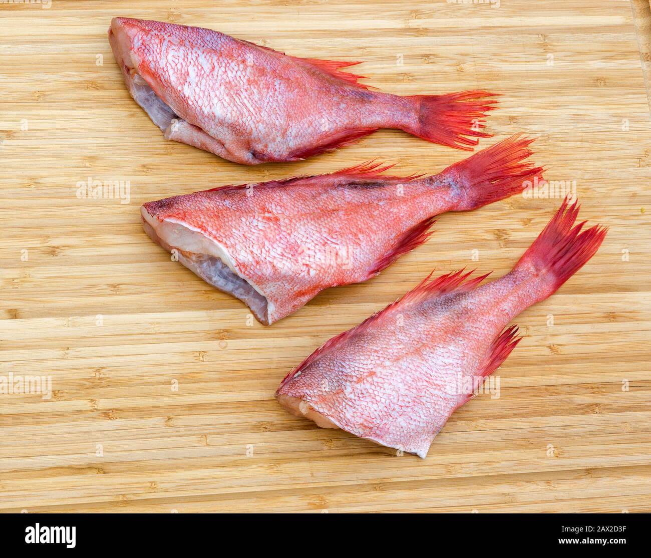 Fresh raw red fish on wooden cutting board. Raw red sea perches. Fish wooden chopping board. Stock Photo