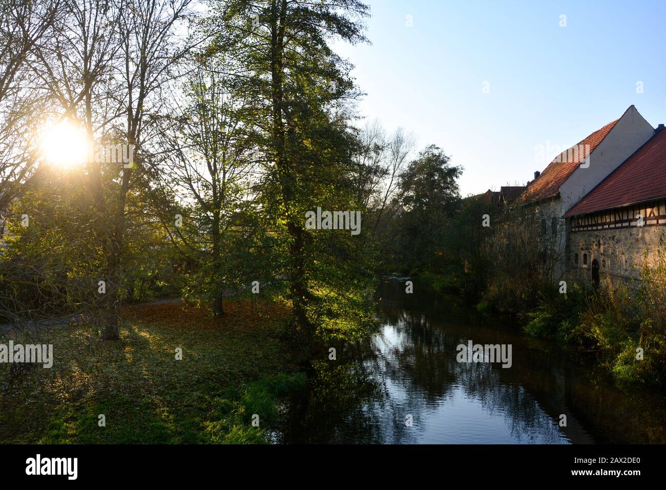 Small stream with nature and old houses in the evening light with sun  in Ostheim , Rhoen, Bavaria, Germany Stock Photo