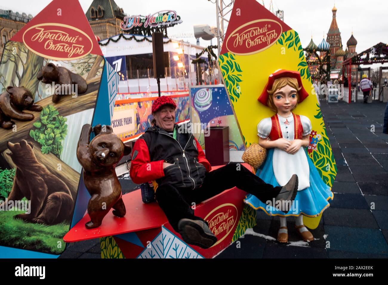 Russian man takes a photo near installations of popular Russian chocolates 'Red October' on 'GUM' ice rink on Red Square  in central Moscow, Russia Stock Photo