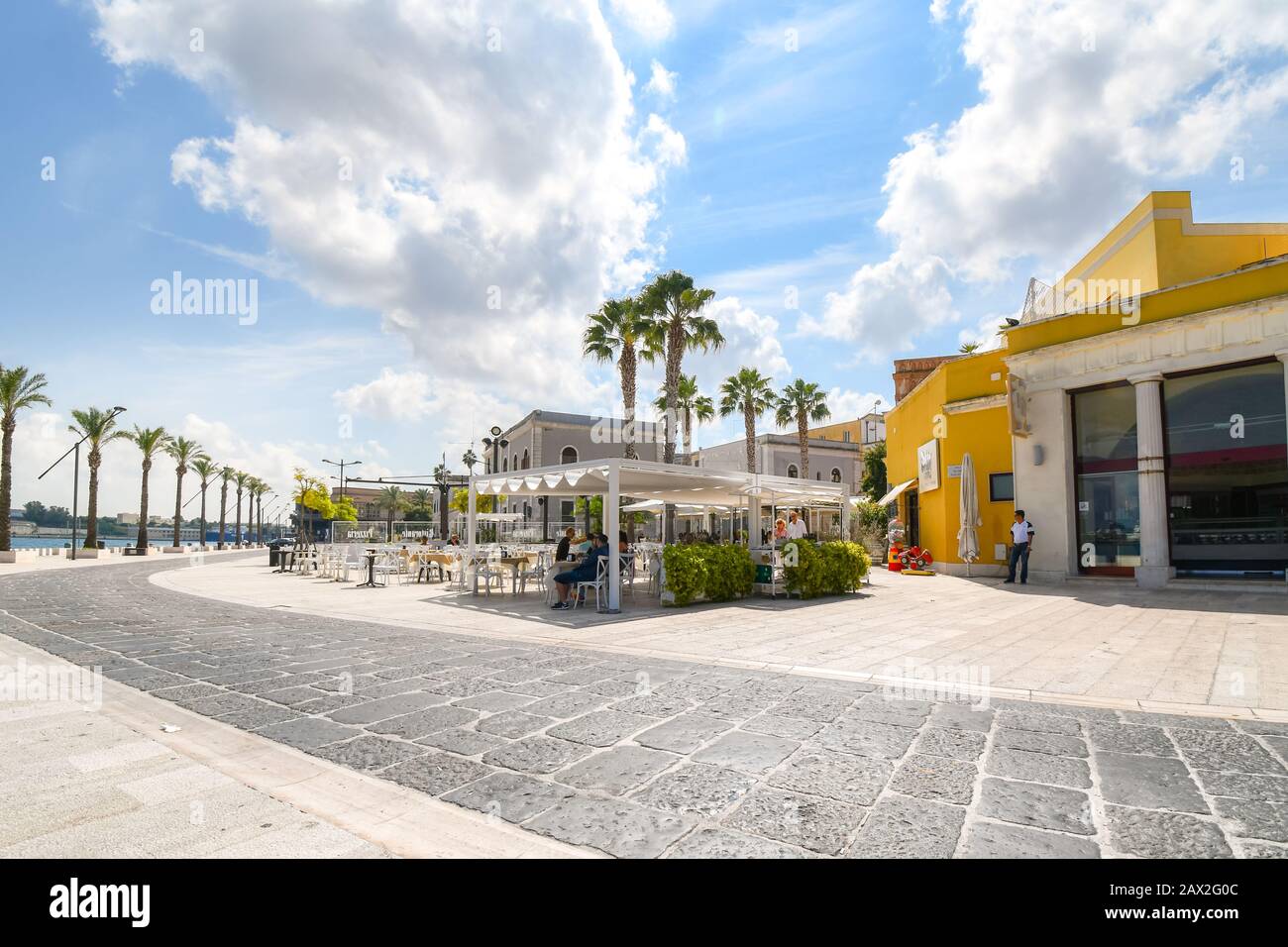 Tourists enjoy a sunny summer day on the waterfront boardwalk at the port city of Brindisi Italy in the region of Puglia Stock Photo