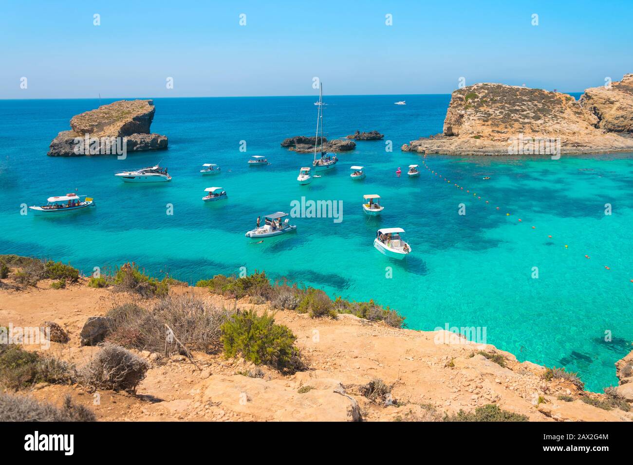 Cove Blue lagoon with anchored boats on Comino island in Malta. Turquoise sea, azure crystal clear ocean, yachts and sailing boats. Stock Photo
