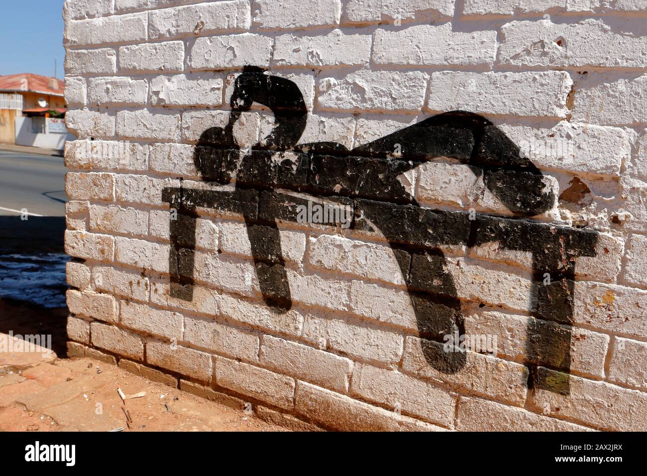 Street art mural in the form of a silhouette depicting a drunken man lying on a bench seeking solace and drinking himself into a stupor Stock Photo