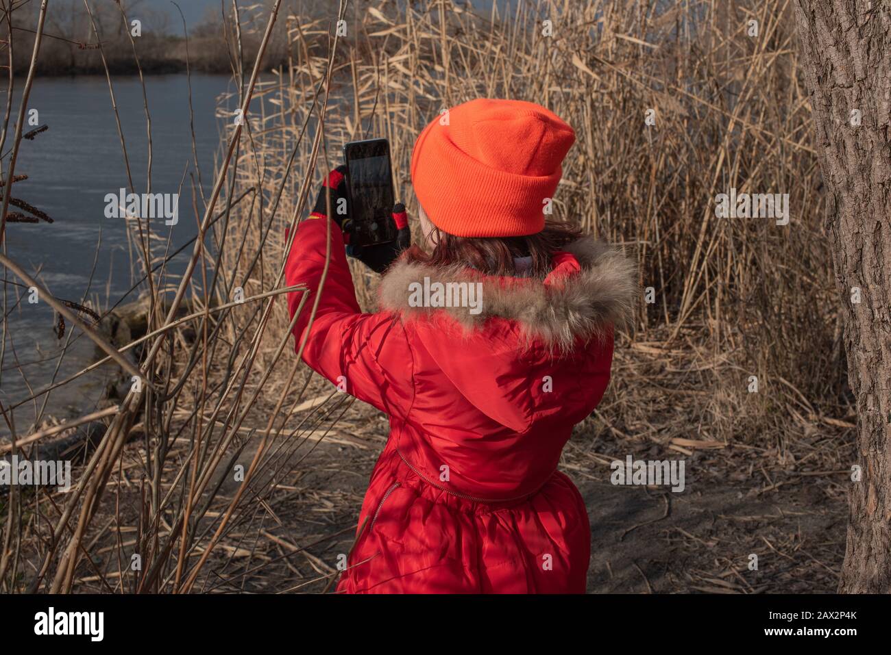 Girl dressed in red jacket, poses for making selfie or photo of herself