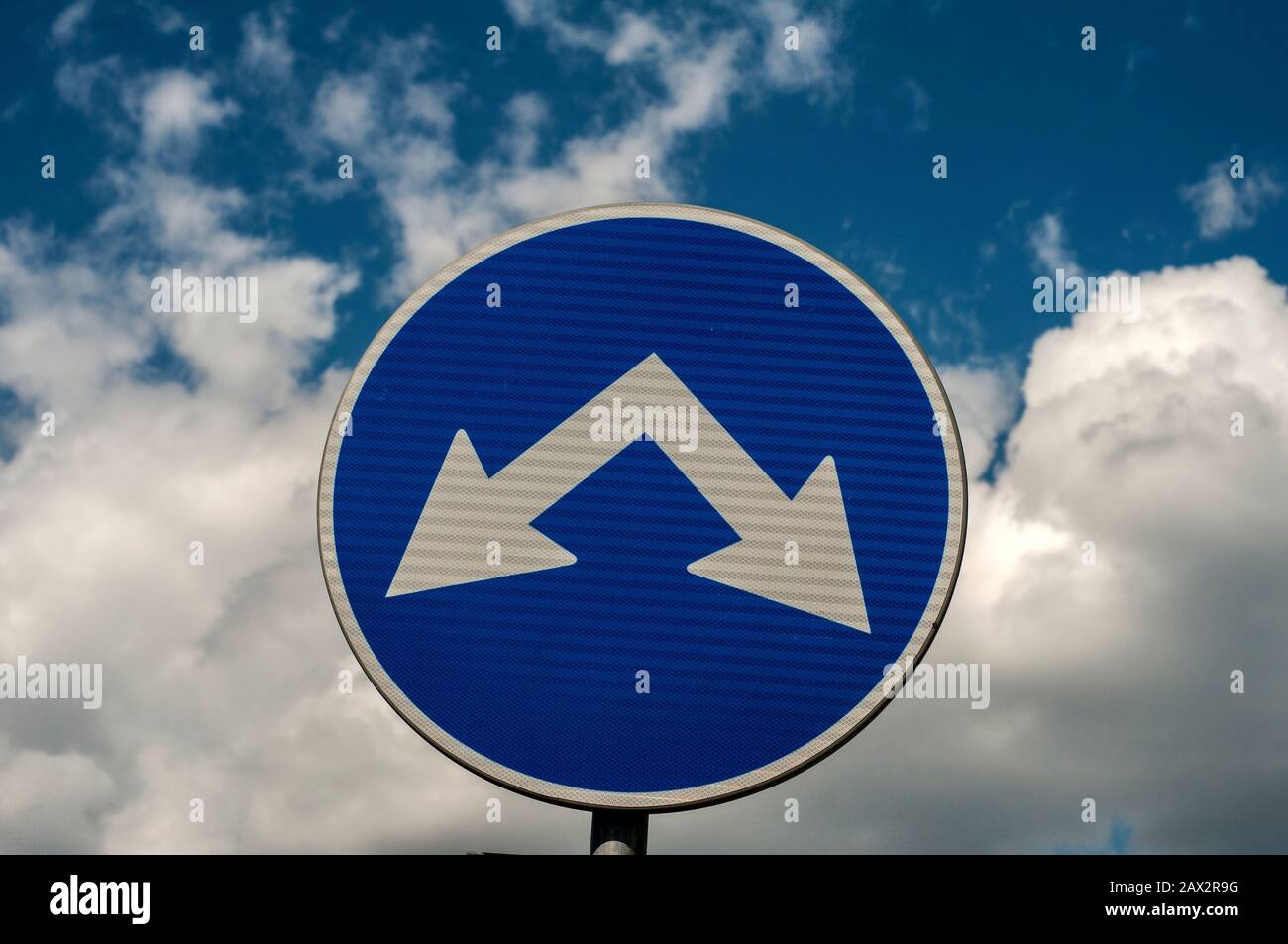 Blue traffic road sign with two arrows for two directions closeup on ...