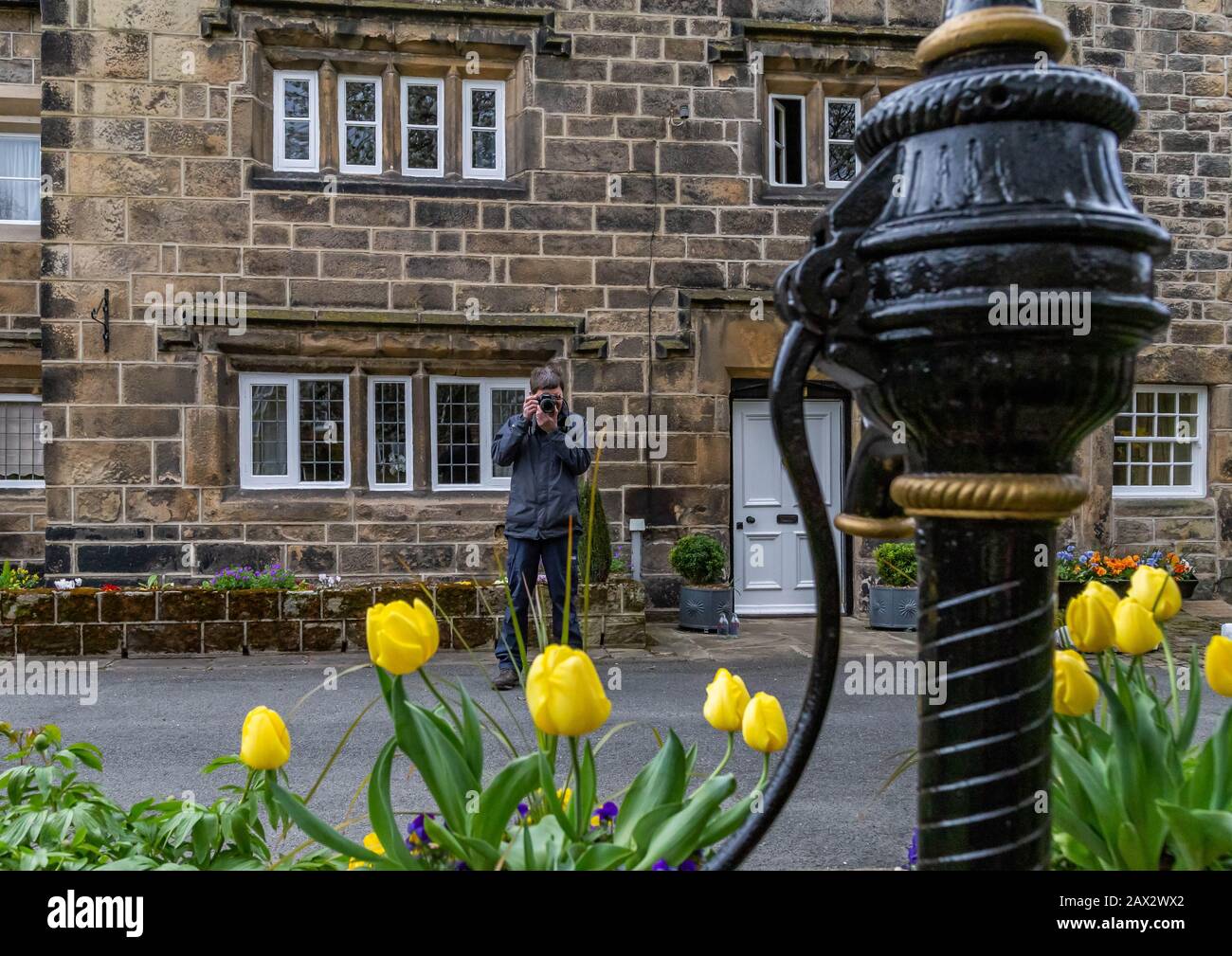 A man takes a photograph of a garden water pump feature in Esholt, Yorkshire, England. Stock Photo