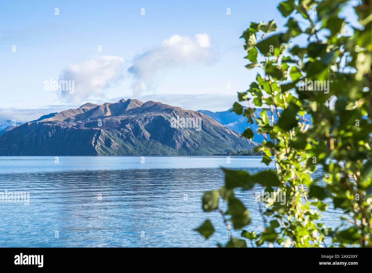 Early morning lake sunrise with golden light. Blue sky and water. Lake Wanaka New Zealand, Popular travel destination. Stock Photo