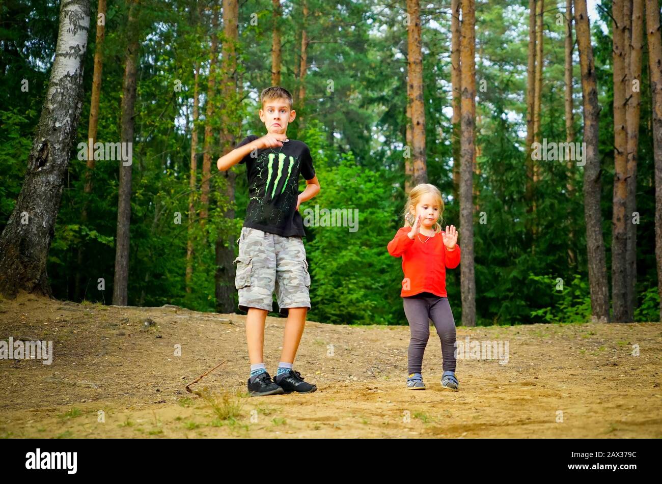 A boy and a girl are dancing merrily in a clearing in the forest Stock Photo